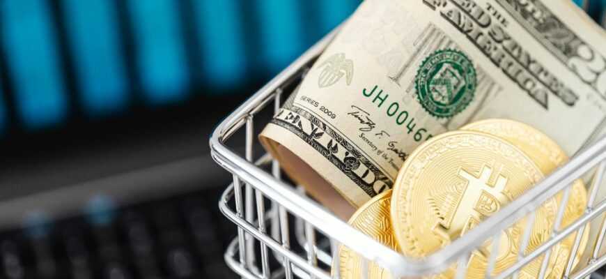 Close-up of bitcoin coins and US dollars in a shopping cart on a laptop, symbolizing digital finance.