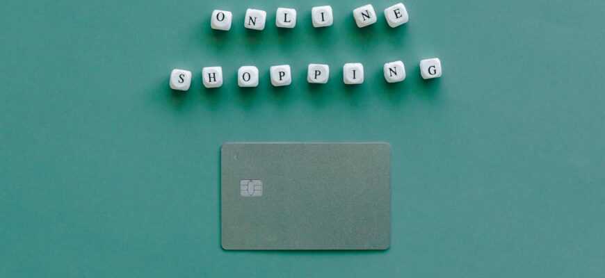 Flat lay of credit card and 'Online Shopping' text on green background, symbolizing ecommerce.