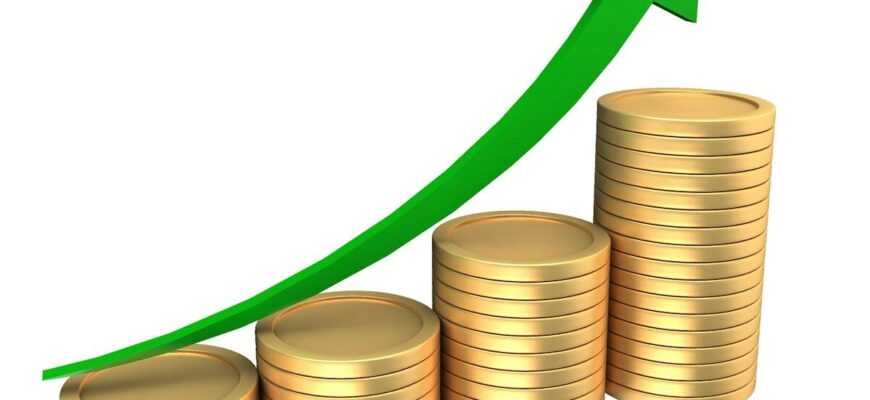 Stacks of coins with an upward trending green arrow