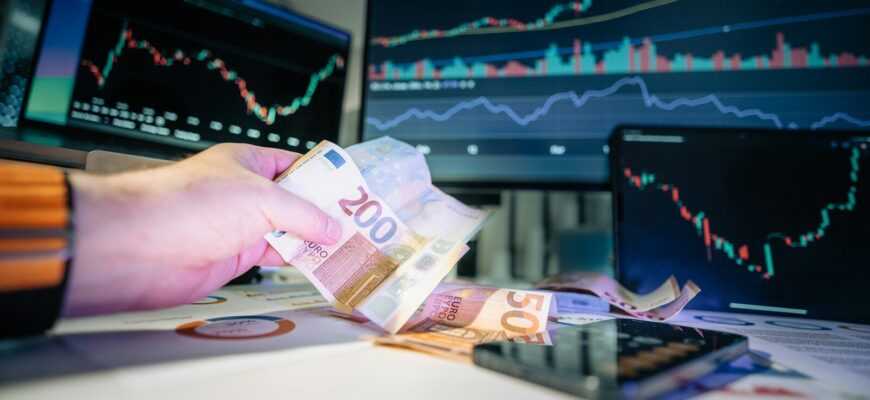 A person holding money in front of a computer screen